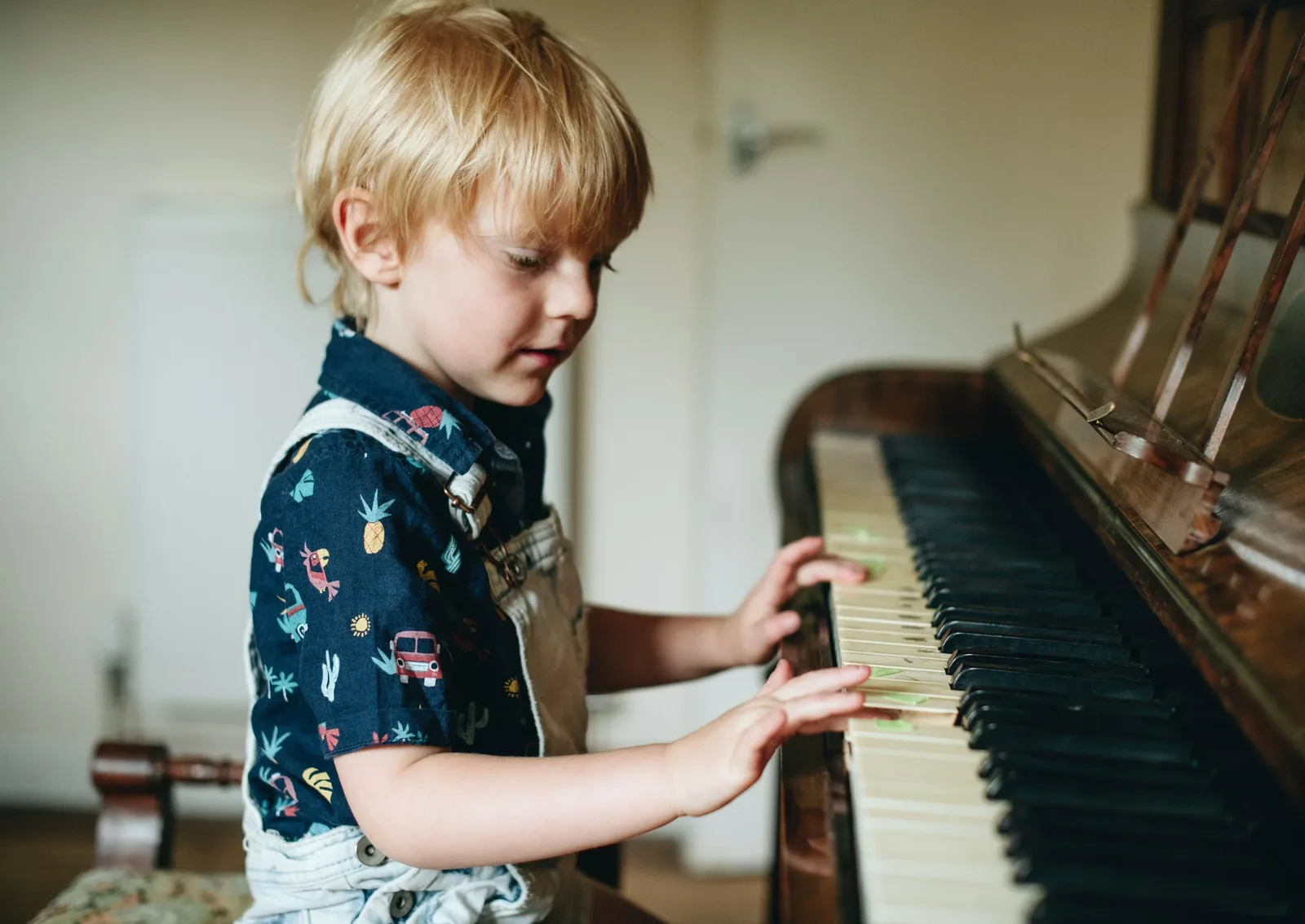 Young child playing an upright piano at home